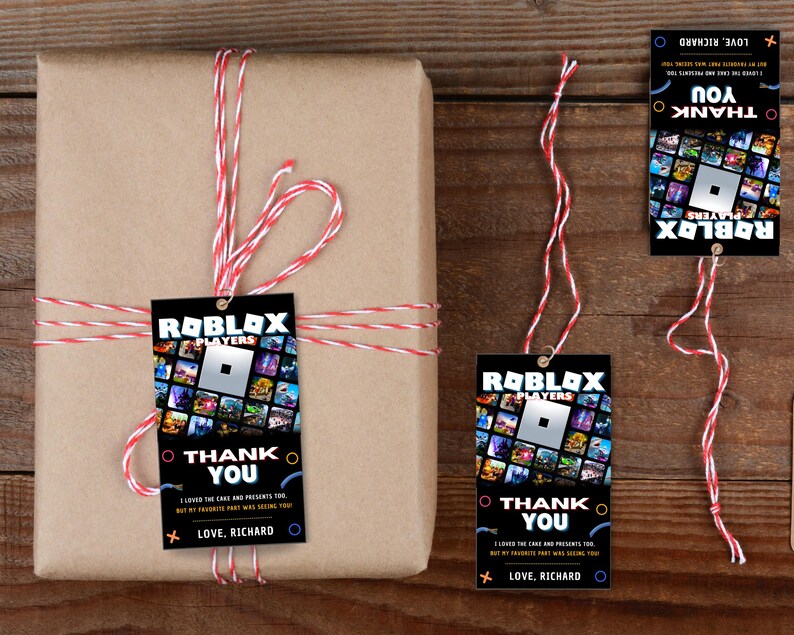 May include: Three black and white thank you tags with a Roblox logo and the text "Roblox Players" and "Thank You". The tags are tied with red and white string to a brown gift box.