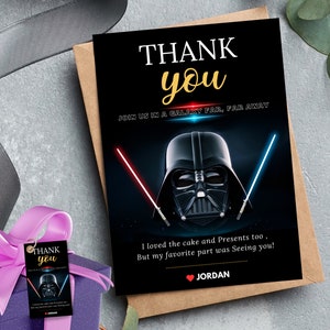 May include: A black and gold "Thank You" card with a Darth Vader graphic and lightsabers. The card reads "Join us in a galaxy far, far away" and "I loved the cake and presents too, but my favorite part was seeing you!"