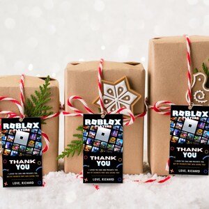 May include: Three brown gift boxes wrapped with red and white twine and decorated with a snowflake, a bird, and a small evergreen tree. Each box has a black gift tag with a Roblox logo and the text "Roblox Players Thank You I loved the cake and presents too but my favourite part was seeing you Love, Richard".