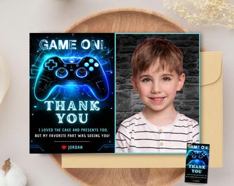 May include: A blue and black gamer themed thank you card with a glowing video game controller graphic. The card says "Game On! Thank You" and has a space for a photo. The text says "I loved the cake and presents too, but my favorite part was seeing you!" and is signed "Jordan".