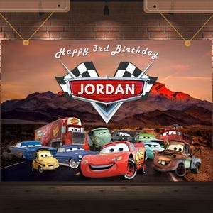 Puede incluir: Un banner de cumplea&ntilde;os con personajes de la pel&iacute;cula Cars, con el texto "Happy 3rd Birthday JORDAN". El fondo muestra un paisaje des&eacute;rtico con monta&ntilde;as y una puesta de sol. El banner incluye a Rayo McQueen y otros personajes de Cars.