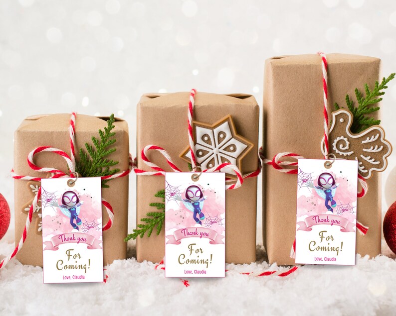 Puede incluir: Tres cajas de regalo marrones con etiquetas de regalo rosas y moradas que representan a un personaje de dibujos animados de una ara&ntilde;a-ni&ntilde;a. Las etiquetas tienen el texto "&iexcl;Gracias por venir! Con cari&ntilde;o, Claudia".