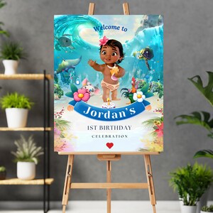 May include: A welcome sign for a 1st birthday party featuring a cartoon character from the movie Moana. The sign is blue and white with a tropical theme and says "Welcome to Jordan's 1st Birthday Celebration".
