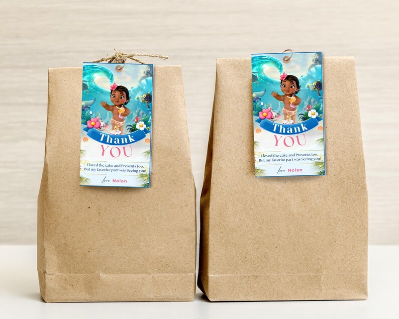 May include: Two brown paper bags with blue and white thank you tags featuring a cartoon character from the movie Moana. The text on the tags reads "Thank You" and "I loved the cake and presents too, but my favorite part was seeing you! for Nolan".