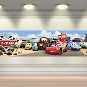 May include: A rectangular horizontal banner featuring a desert landscape with various anthropomorphic car characters. The text Happy 3rd Birthday and the name JORDAN are displayed on a racing-themed emblem with checkered flags on the left side.