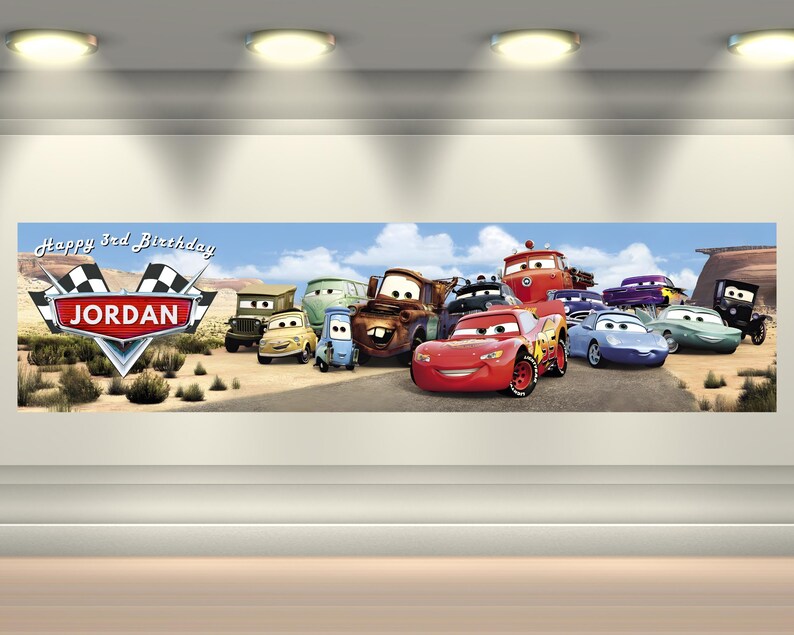May include: A rectangular horizontal banner featuring a desert landscape with various anthropomorphic car characters. The text Happy 3rd Birthday and the name JORDAN are displayed on a racing-themed emblem with checkered flags on the left side.