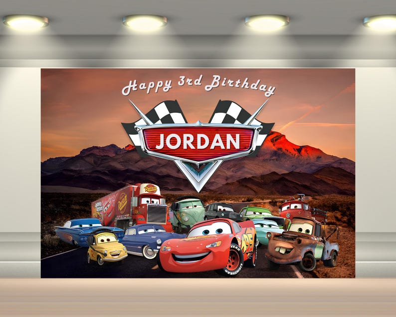 Puede incluir: Un tel&oacute;n de fondo con los personajes animados de Cars con una escena de monta&ntilde;a des&eacute;rtica. La pancarta dice "Happy 3rd Birthday JORDAN" con un emblema de bandera de carreras. La imagen incluye a Rayo McQueen y otros veh&iacute;culos.