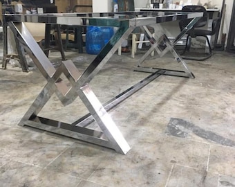 May include: A polished chrome table base with a geometric design. The base is made of thick metal and has a modern, industrial look.