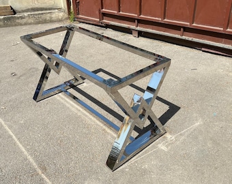 May include: A polished chrome table base with a geometric design. The base is made of metal and has a shiny finish.