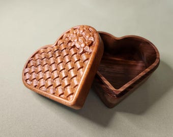 May include: A wooden heart-shaped box with a carved floral design on the lid. The box is open, revealing the empty interior.