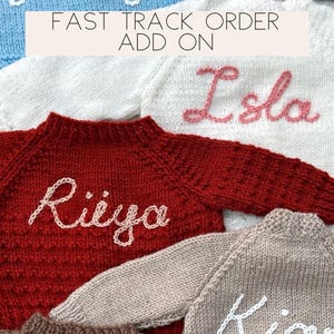 May include: A close-up of five knitted jumpers with different names embroidered on them. The jumpers are in various colours, including red, white, blue, beige, and brown. The text "FAST TRACK ORDER ADD ON" is displayed on a pink banner.