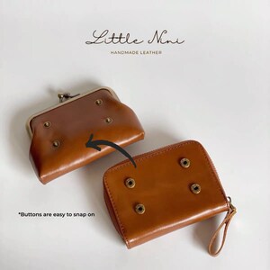 May include: Two brown leather wallets with metal snaps and rivets. The smaller wallet has a fold-over closure and the larger wallet has a zipper closure. "Buttons are easy to snap on" is written below the wallets.