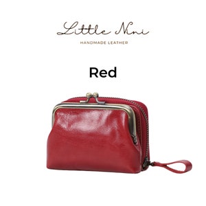 May include: A red leather coin purse with a brass frame and zipper closure. The purse has a small handle on the side. The text "Little Nini Handmade Leather" and "Red" are visible above the purse.