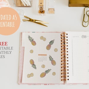 May include: An open A5 spiral-bound planner with pineapple illustrations and the text "UNDATED A5 PRINTABLE" and "+ FREE PRINTABLE MONTHLY TITLES". The planner is open to a dotted grid page with a calendar and a page for notes.