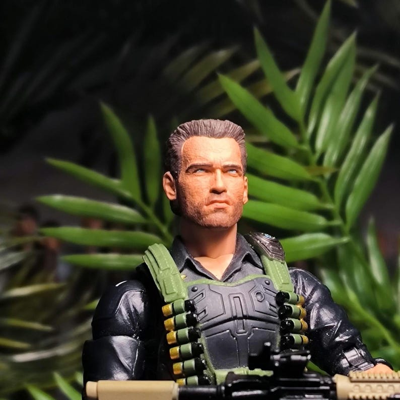 May include: A close-up of a military action figure wearing a black jacket, green vest, and holding a black and tan rifle. The figure has a serious expression on its face and is wearing a black shirt underneath the jacket.
