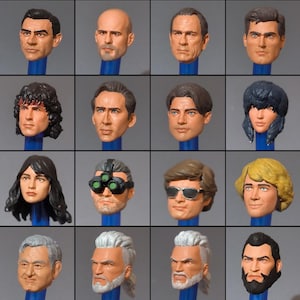 Puede incluir: Una colección de dieciséis cabezas detalladas de figuras de acción, cada una montada en un pasador azul. Las cabezas representan a varios personajes masculinos con diferentes peinados, expresiones faciales y accesorios, como gafas de sol y gafas de visión nocturna.