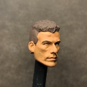 Puede incluir: Primer plano de una escultura de cabeza de plástico pintada de un hombre con el pelo corto y castaño. La cabeza está pintada con tonos de piel realistas y rasgos.