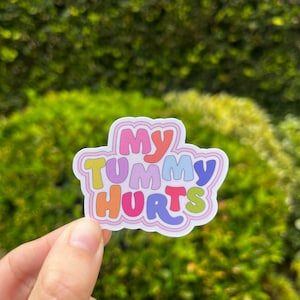 May include: A colorful sticker with the text "My Tummy Hurts" in a playful font.