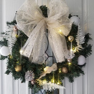 Gold and white pre-lit Christmas wreath with big bow, feathers and sparkly bird