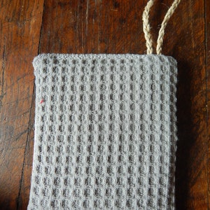 May include: A gray waffle weave kitchen towel with a knotted rope handle.