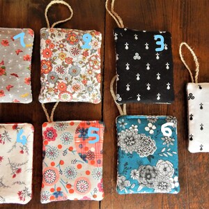 May include: Ten fabric pouches with different patterns, each with a string loop at the top. The pouches are numbered 1 through 10.