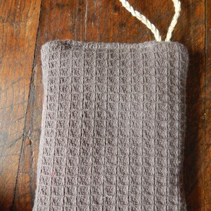 May include: A gray waffle weave kitchen scrubby with a white cotton loop handle.