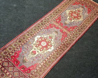 May include: A red, beige, and gray patterned runner rug with a floral design. The rug has a fringed edge.