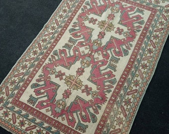 May include: A vintage Turkish rug with a cream background and a geometric pattern in shades of red, blue, and green. The rug has a border with a repeating star design.