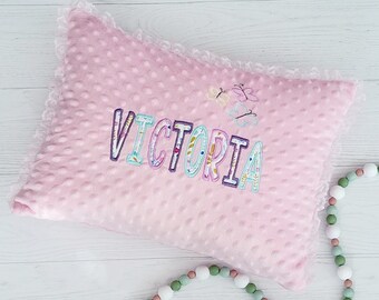 May include: A pink pillow with white lace trim and the name "VICTORIA" embroidered in colorful letters. The pillow is decorated with small butterfly designs.