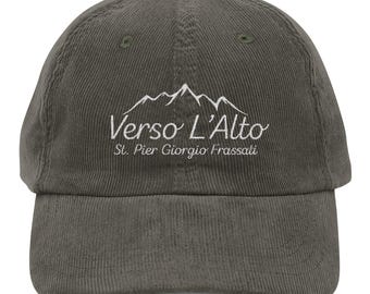 May include: Olive green corduroy baseball cap with the text "Verso L'Alto" and "St. Pier Giorgio Frassati" embroidered in white. The cap features a mountain range graphic above the text.