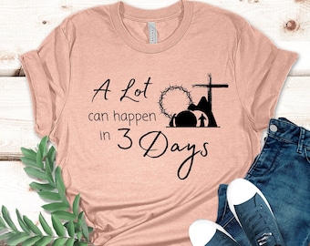 Pode incluir: Uma camiseta cor de pêssego com o texto "A Lot can happen in 3 Days" em escrita preta. A camisa é combinada com jeans azuis e tênis azul escuro com solas brancas. Um ramo de folhas verdes está no lado esquerdo.