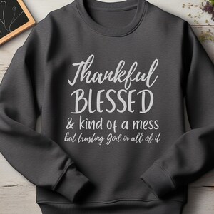 May include: A dark gray sweatshirt with the text "Thankful Blessed & kind of a mess but trusting God in all of it" printed in white.