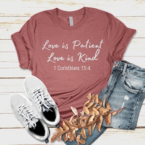 Pode incluir: Uma camiseta marrom-avermelhada com texto branco que diz "Love is Patient Love is Kind 1 Corinthians 13:4".