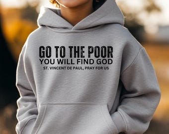 May include: A light gray hoodie with a front pocket and the text "GO TO THE POOR YOU WILL FIND GOD ST. VINCENT DE PAUL, PRAY FOR US" in black. The hoodie is worn by a person.