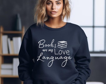 May include: A navy blue sweatshirt with the text "Books are my Love Language" in white lettering. The text is accompanied by a graphic of a stack of books.