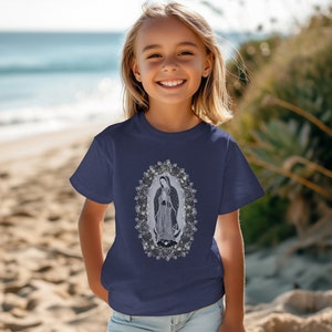 May include: A navy blue t-shirt with a white graphic of Our Lady of Guadalupe surrounded by roses.