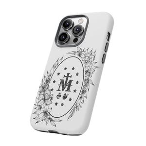 K&ouml;nnte beinhalten: Wei&szlig;es Handy-Case mit einem schwarz-wei&szlig;en Blumendesign, das die Wunderbare Medaille zeigt. Die Medaille hat ein Kreuz und die Buchstaben "M" und "A" in einem Kreis.