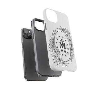 K&ouml;nnte beinhalten: Eine wei&szlig;e iPhone-H&uuml;lle mit einem schwarz-wei&szlig;en Blumendesign, das die Wundermedaille zeigt. Die Medaille zeigt eine Darstellung der Jungfrau Maria mit einem Kreuz und den Buchstaben "M" und "A".