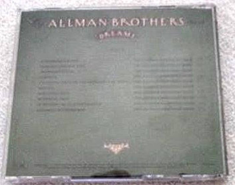 K&ouml;nnte beinhalten: Die R&uuml;ckseite einer CD-H&uuml;lle f&uuml;r das Album "Dream" der Allman Brothers Band. Das Cover ist in ged&auml;mpftem Gr&uuml;n gehalten, mit dem Namen der Band und dem Albumtitel in goldfarbenen Buchstaben. Songtitel sind unten aufgef&uuml;hrt.