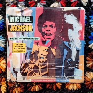 May include: A vintage Michael Jackson record sleeve. The cover features a colorful illustration of Jackson with the text "MICHAEL JACKSON" and "TWENTY-FIVE MILES." It also includes the text "NEVER BEFORE RELEASED FROM THE MOTOWN VAULTS."