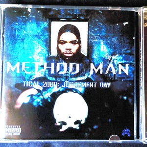 May include: A music CD case featuring the album cover for Method Man Tical 2000: Judgement Day. The cover displays a person in a dark hood against a blue, textured background, with a white skull graphic at the bottom and Parental Advisory text.