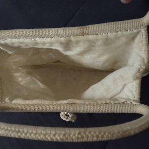 May include: A white woven handbag with a single handle. The bag is open and the inside is lined with white fabric.