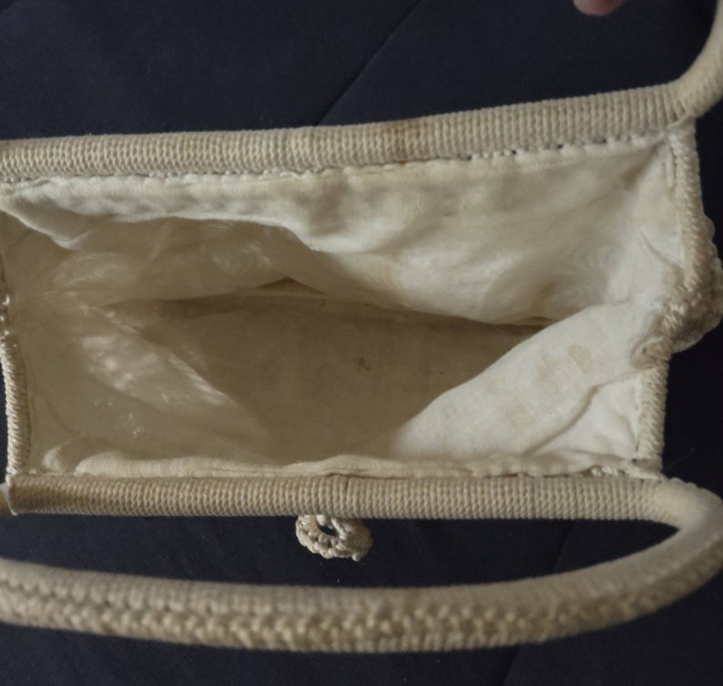 May include: A white woven handbag with a single handle. The bag is open and the inside is lined with white fabric.