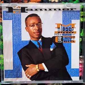 May include: CD case featuring MC Hammer. The album cover has a portrait of the artist wearing glasses and a suit. The album title is "Please Hammer Don't Hurt 'Em" with a blue and orange color scheme.