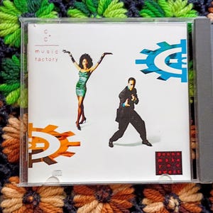 May include: A CD case featuring the album cover for C+C Music Factory. The cover art includes a woman in a green dress, a man in a black suit, and the text "music factory." The album title is "Gonna Make You Sweat."