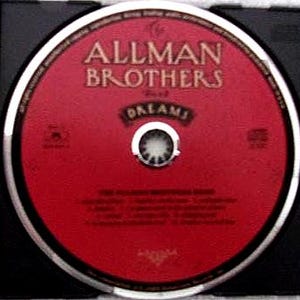 K&ouml;nnte beinhalten: Eine CD mit roter Oberfl&auml;che, auf der der Text "ALLMAN BROTHERS" und "DREAMS" in einer Serifenschrift steht. Die Disc befindet sich in einer schwarzen H&uuml;lle. Sie hat einen silbernen Rand und eine silberne Mitte.