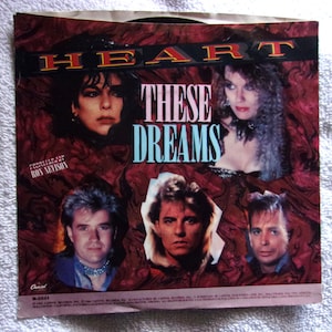 May include: A vinyl record cover featuring the band Heart. The cover is red with a swirling pattern and features a photo of the band members. The title of the album is "These Dreams".