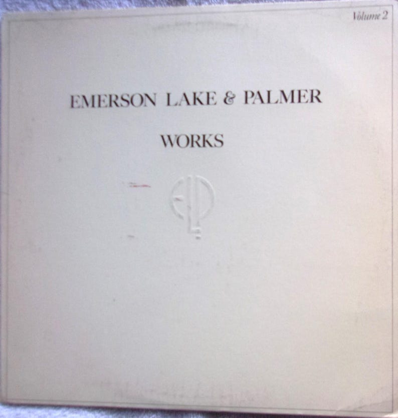 Puede incluir: Una portada de &aacute;lbum de vinilo blanco con el texto "Emerson Lake & Palmer" y "Works" en letras marrones. La portada del &aacute;lbum tambi&eacute;n presenta un c&iacute;rculo blanco con las letras "ELP" en una fuente estilizada.