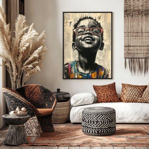 Op de afbeelding: Een ingelijste kunstdruk met een zwart-wit portret van een lachend kind met een oranje bril. Het kind kijkt omhoog, met een kleurrijk shirt. De achtergrond is een collage van krantenknipsels.