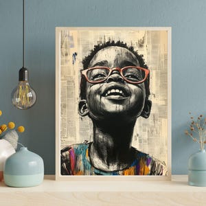 Op de afbeelding: Een ingelijste kunstdruk met een zwart-wit illustratie van een lachend kind met een oranje bril. Het shirt van het kind heeft kleurrijke strepen. De achtergrond is een collage van krantenknipsels.